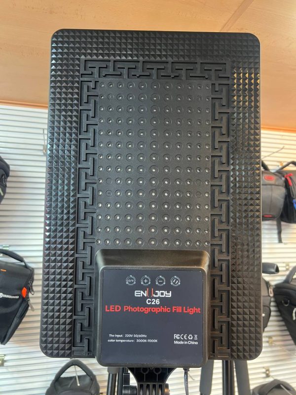 ور LED حرفه‌ای مدل C26 نصب‌شده روی سه‌پایه در یک استودیو عکاسی، در حال نورپردازی پرتره از یک مدل نشسته با نور نرم و یکنواخت.